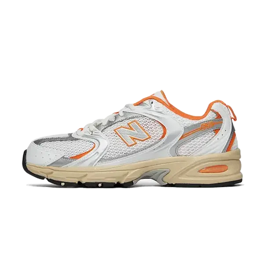 De New Balance 530 Sunglow/White van New Balance is een witte en grijze atletische sneaker met oranje accenten en een beige zool. Hij heeft mesh-panelen, een vetersluiting en een merklogo "N" op de zijkant.